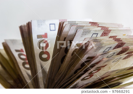 Ukrainian paper money is laid out on a blue background. 100 hryvnia banknotes 97668291