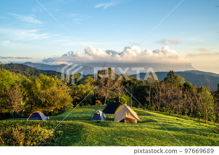 View of Doi Luang Chiang Dao, the third highest mountain in Thailand, seen with dramatic clouds and colorful sky with camping tents in foreground View of Doi Luang Chiang Dao, the third highest mountain in Thailand, seen with dramatic clouds and colorful sky with camping tents in foreground 97669689