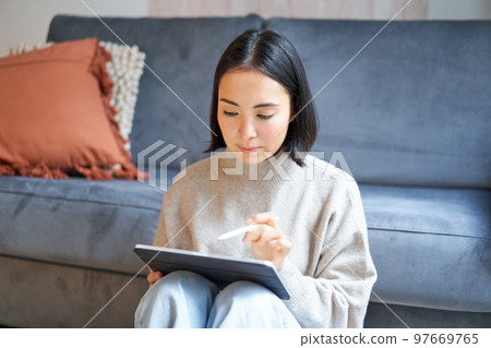 Creative young woman sitting with tablet and pen, drawing on digital application Creative young woman sitting with tablet and pen, drawing on digital application 97669765