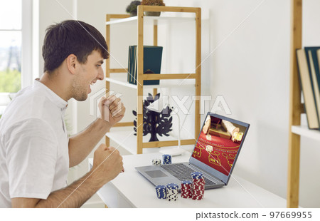Excited guy is amazed at big win he won playing online poker with help of laptop. 97669955