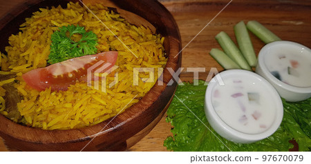 Rice lamb biryani pilaf with lamb or mutton meat and vegetables cucumber along with yoghurt in a very nice american restaurant Rice lamb biryani pilaf with lamb or mutton meat and vegetables cucumber along with yoghurt in a very nice american restaurant 97670079