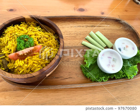 Rice lamb biryani pilaf with lamb or mutton meat and vegetables cucumber  along with yoghurt in a very nice american restaurant 97670080