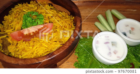 Rice lamb biryani pilaf with lamb or mutton meat and vegetables cucumber along with yoghurt in a very nice american restaurant Rice lamb biryani pilaf with lamb or mutton meat and vegetables cucumber along with yoghurt in a very nice american restaurant 97670081