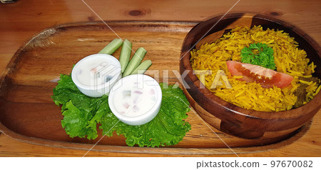 Rice lamb biryani pilaf with lamb or mutton meat and vegetables cucumber along with yoghurt in a very nice american restaurant Rice lamb biryani pilaf with lamb or mutton meat and vegetables cucumber along with yoghurt in a very nice american restaurant 97670082
