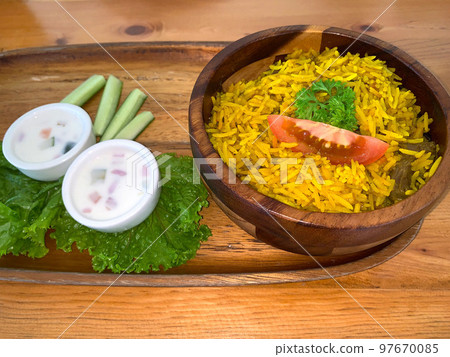 Rice lamb biryani pilaf with lamb or mutton meat and vegetables cucumber along with yoghurt in a very nice american restaurant Rice lamb biryani pilaf with lamb or mutton meat and vegetables cucumber along with yoghurt in a very nice american restaurant 97670085