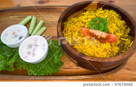 Rice lamb biryani pilaf with lamb or mutton meat and vegetables cucumber along with yoghurt in a very nice american restaurant Rice lamb biryani pilaf with lamb or mutton meat and vegetables cucumber along with yoghurt in a very nice american restaurant 97670086