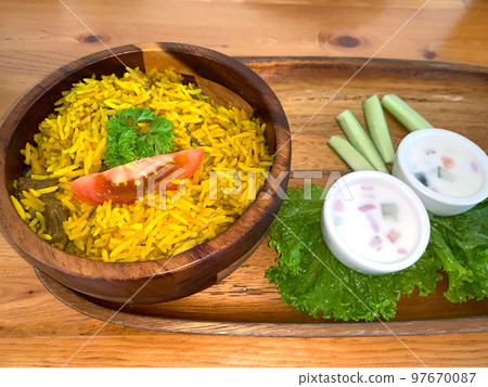 Rice lamb biryani pilaf with lamb or mutton meat and vegetables cucumber along with yoghurt in a very nice american restaurant Rice lamb biryani pilaf with lamb or mutton meat and vegetables cucumber along with yoghurt in a very nice american restaurant 97670087