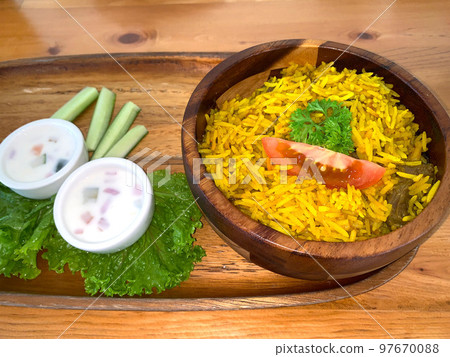Rice lamb biryani pilaf with lamb or mutton meat and vegetables cucumber along with yoghurt in a very nice american restaurant Rice lamb biryani pilaf with lamb or mutton meat and vegetables cucumber along with yoghurt in a very nice american restaurant 97670088