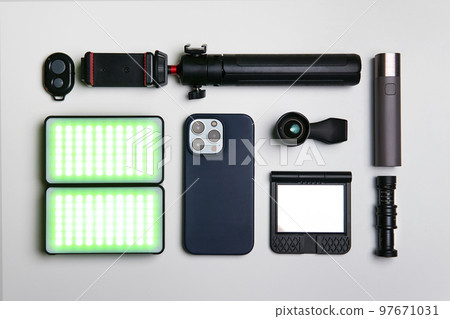 Equipment for shooting video on a smartphone. Microphone, LED lamp, tripod, lens smartphone are on a white table Equipment for shooting video on a smartphone. Microphone, LED lamp, tripod, lens smartphone are on a white table 97671031