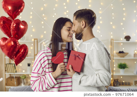 Happy loving couple celebrating Valentine's Day, hugging, kissing, and exchanging presents 97671064