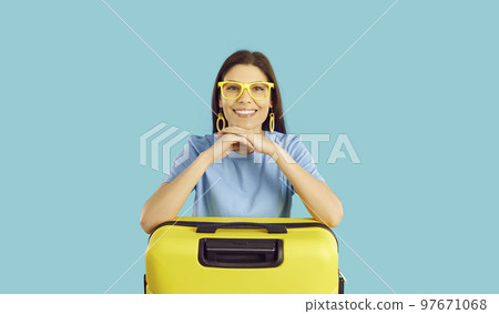 Portrait of happy beautiful young woman traveler with yellow suitcase on light blue background. Portrait of happy beautiful young woman traveler with yellow suitcase on light blue background. 97671068