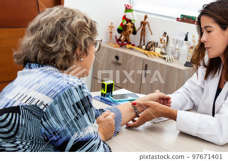 Traumatologist female doctor at her office examining a senior female patient. Skeleton bone disease exam and medic aid. Career concept. Traumatologist female doctor at her office examining a senior female patient. Skeleton bone disease exam and medic aid. Career concept. 97671401