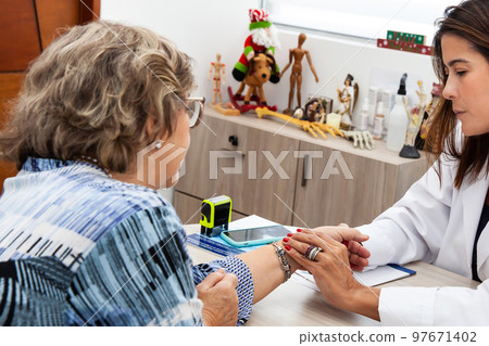 Traumatologist female doctor at her office examining a senior female patient. Skeleton bone disease exam and medic aid. Career concept. 97671402