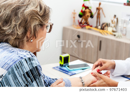 Senior female patient in consultation with a traumatologist female doctor. Skeleton bone disease exam and medic aid. Insurance concept Senior female patient in consultation with a traumatologist female doctor. Skeleton bone disease exam and medic aid. Insurance concept 97671403