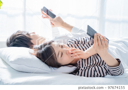 couple looking at smartphone in bed 97674155