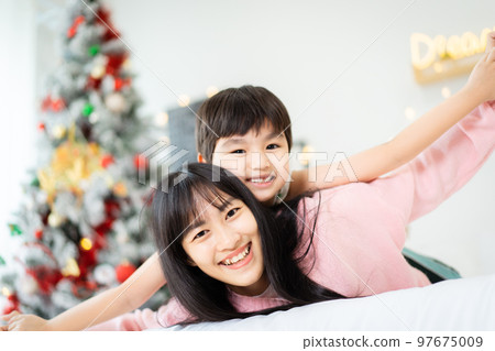 Woman and son relaxing together in bedroom. 97675009