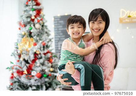 Woman and son relaxing together in bedroom. 97675010