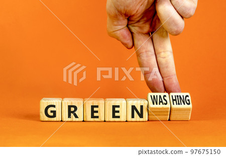 Green or greenwashing symbol. Concept words Green and Greenwashing on wooden cubes. Businessman hand. Beautiful orange table orange background. Business green greenwashing concept. Copy space. 97675150