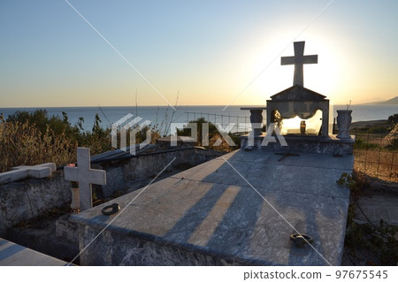 Cross on a grave in a Greek cemetery at dawn 97675545