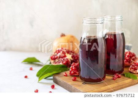 Healthy drink diet immunity vitamins or vegetarian food concept. Pomegranate juice in glass bottles and fresh pomegranate fruits. Copy space. Healthy drink diet immunity vitamins or vegetarian food concept. Pomegranate juice in glass bottles and fresh pomegranate fruits. Copy space. 97675712