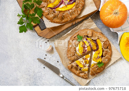 Homemade pumpkin Galette. Healthy homemade wholegrain vegan vegetarian pie (galette) with pumpkin and ricotta cheese on a stone table. View from above. Copy space. 97675718