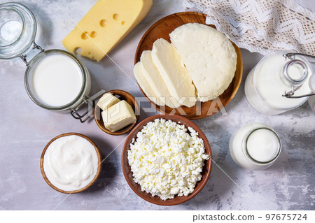 Set of different dairy products (milk, sour cream, cottage cheese, yogurt and butter) on a light stone countertop. Top view flat lay. 97675724