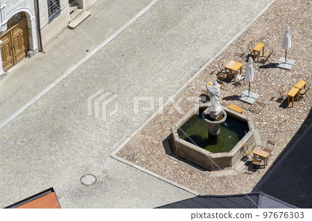 Aerial view of the cafe tables around the fountain on the square, sunny summer day Aerial view of the cafe tables around the fountain on the square, sunny summer day 97676303