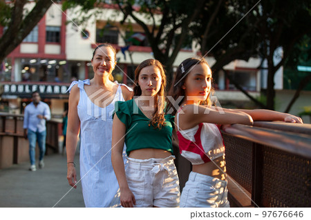 Tourists at one of the bridges along the Cali River Boulevard in the city of Cali in Colombia. Mother and teenager daughters traveling concept. Happy family concept. 97676646