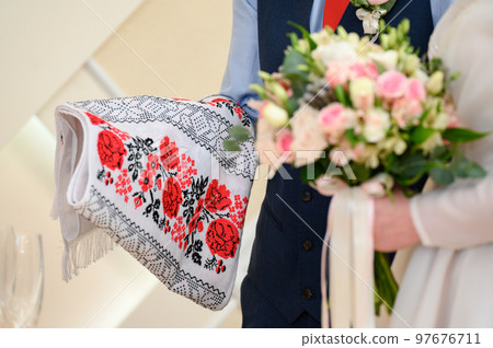 The bridegroom holds an embroidered towel and the bride of flowers, a wedding ceremony. The bridegroom holds an embroidered towel and the bride of flowers, a wedding ceremony. 97676711
