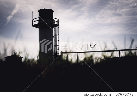 Defocused foreground with industrial emergency flare standing out against an open sky Defocused foreground with industrial emergency flare standing out against an open sky 97676775