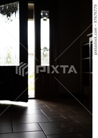 Track of small child footprints visible on a tile floor with an open door letting in light in the background 97676779