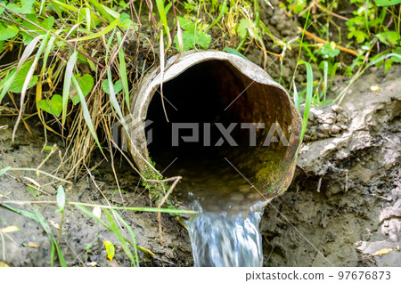 Water flowing from the open outlet of a metal agriculture drainage tile 97676873