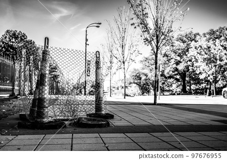 Open cover on a sidewalk access panel with hazard cones and fencing. Open cover on a sidewalk access panel with hazard cones and fencing. 97676955
