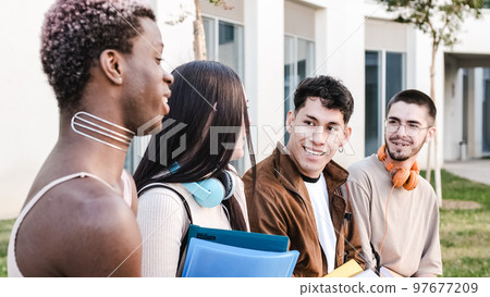 Group of friends smiling and chatting sitting outdoors 97677209