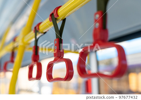 Handle on the bus. Red plastic handrail close-up. 97677432