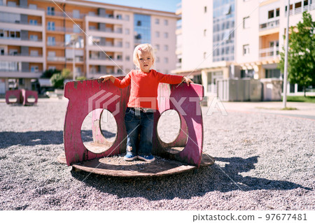 Little girl stands leaning her back on the partitions of a round carousel. High quality photo Little girl stands leaning her back on the partitions of a round carousel. High quality photo 97677481