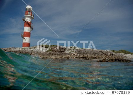Lighthouse on a rocky shore in Cancun. Clear sky and blue sea. Mexico. 97678329