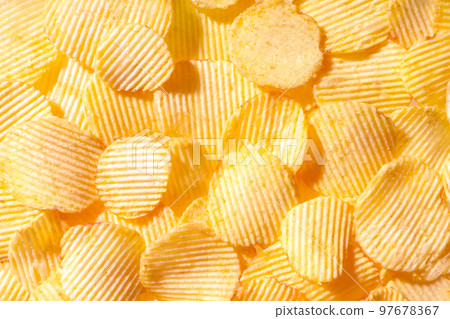 Yellow crispy ridged potato chips close up. Food background Yellow crispy ridged potato chips close up. Food background 97678367