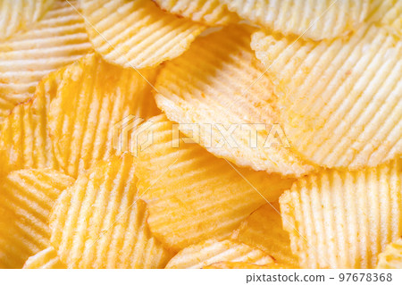Yellow crispy ridged potato chips close up. Food background 97678368