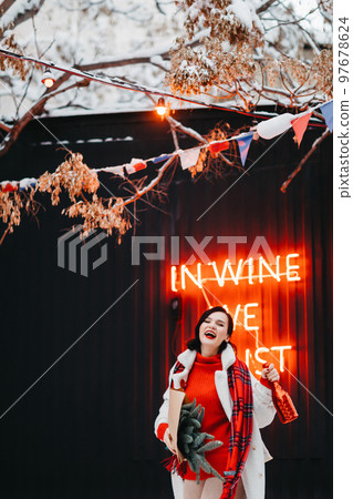 an attractive brunette woman with champagne and a bouquet of spruce branches. 97678624