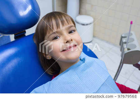 A portrait of a little girl patient in a dental chair in a dentists office A portrait of a little girl patient in a dental chair in a dentists office 97679568