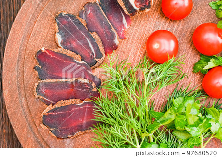 Close up of assorted sliced dry-cured meat on the wooden plate background Close up of assorted sliced dry-cured meat on the wooden plate background 97680520