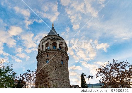 View of Galata Tower from below surrounded by classic buildings against blue sky 97680861