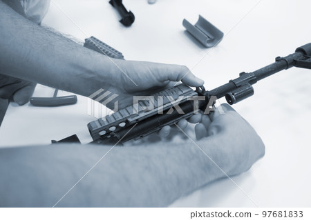 3D printed weapon parts. Man assembles weapon rifle, some parts printed on 3D printer. Details of gray color of weapon printed on 3D printer from polyamide powder. Progressive additive technology 97681833