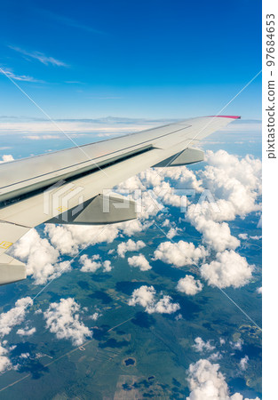View from the airplane window at a beautiful cloudy sky and the airplane wing View from the airplane window at a beautiful cloudy sky and the airplane wing 97684653