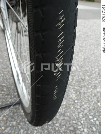 Bicycle wheel on the verge of puncture due to worn treads showing the casing fibers inside the rubber of the tire Bicycle wheel on the verge of puncture due to worn treads showing the casing fibers inside the rubber of the tire 97687141