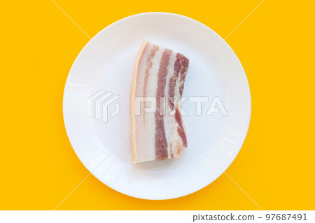 Streaky pork in white plate on yellow background. 97687491