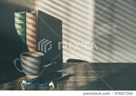 Light by the window, a cup and a smartphone 97687566