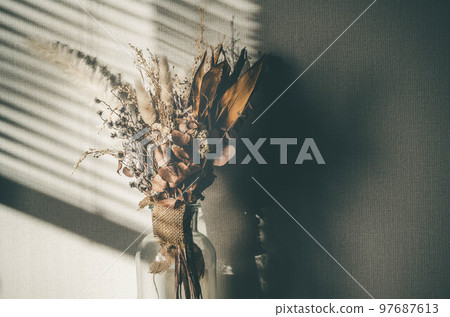 Light by the window, dried flowers, books and cups 97687613
