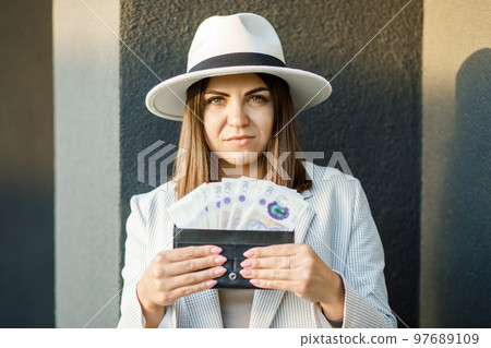 Young business woman holding black wallet with pounds in hands, close up of female hands. The concept of cash payments, savings and salaries Young business woman holding black wallet with pounds in hands, close up of female hands. The concept of cash payments, savings and salaries 97689109